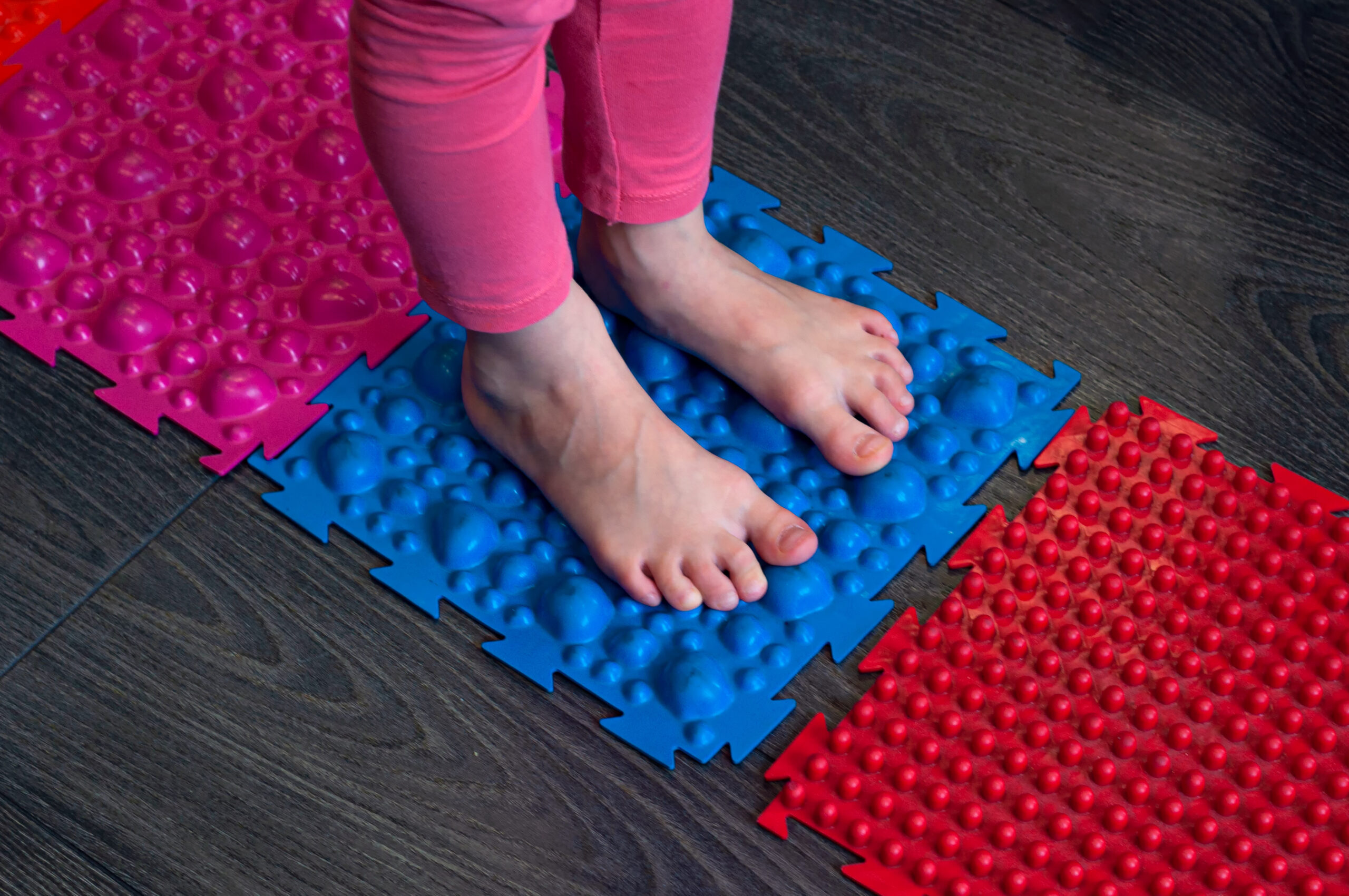 barefoot girl walks on sensory mats in the sensory integration room